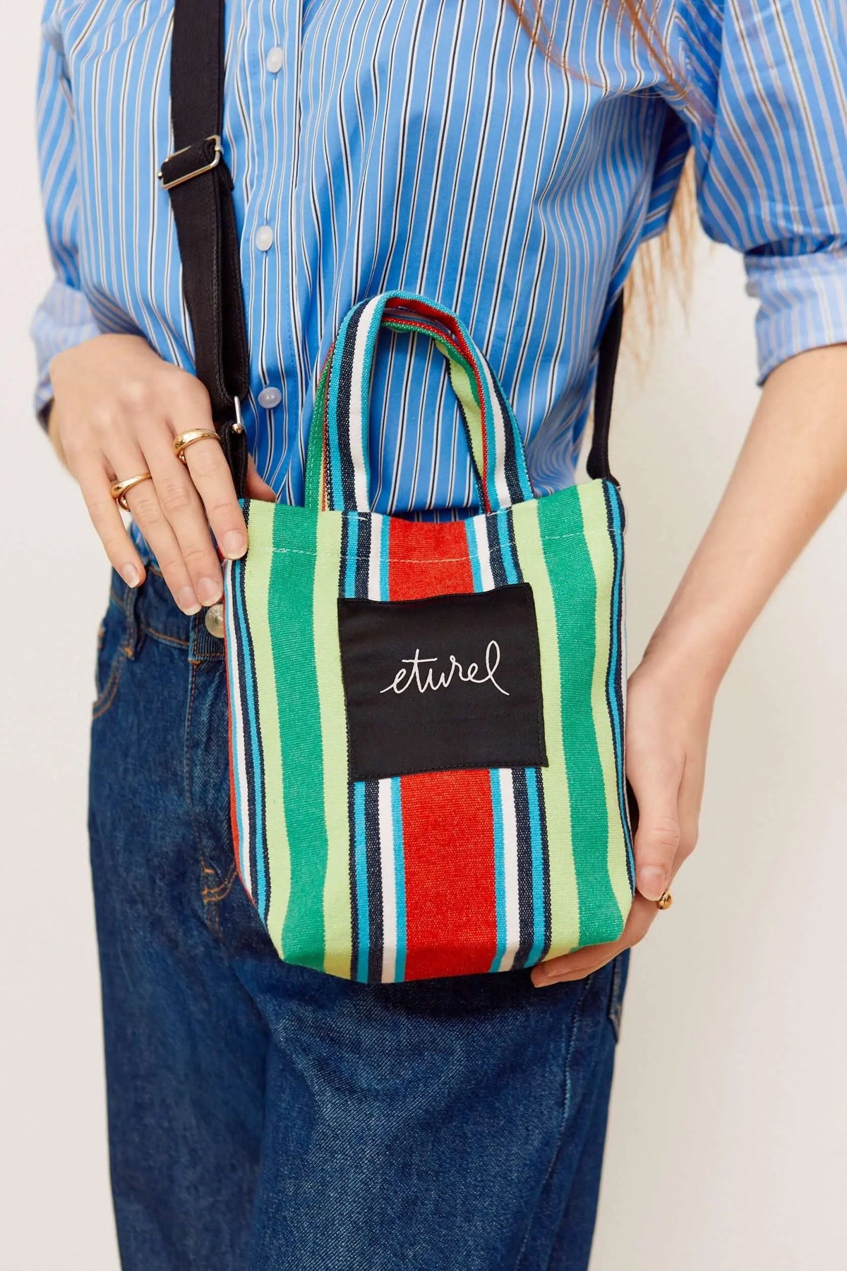 Mini striped canvas crossbody bag in red, green, and blue with top handles and a black branded patch.