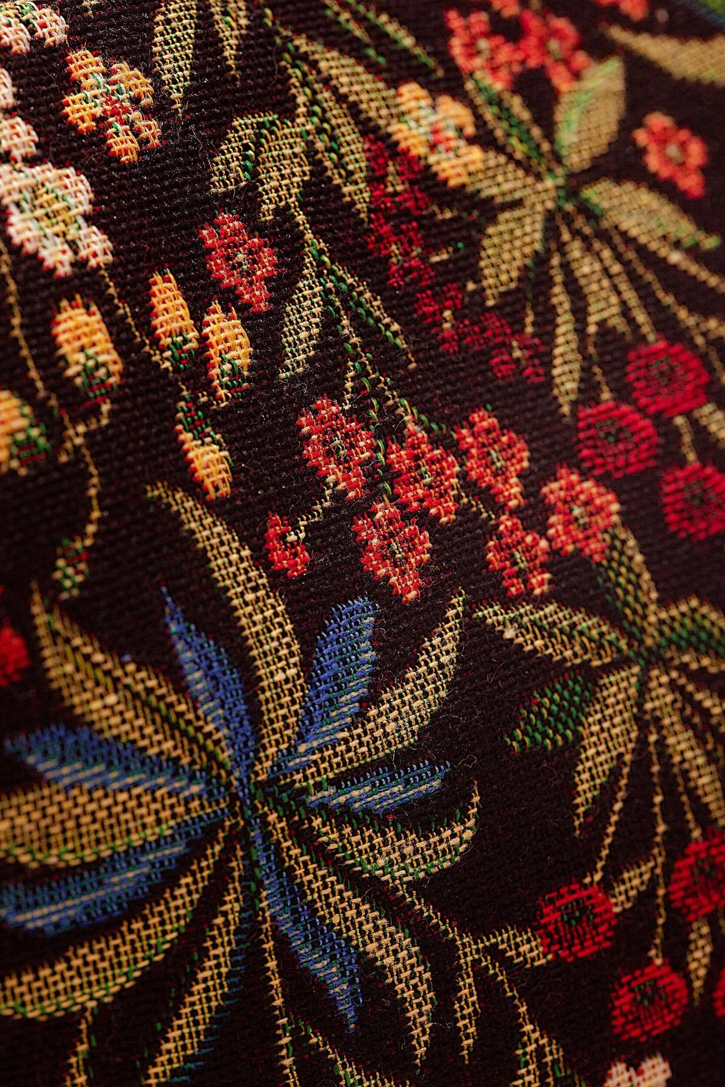 Bolso bandolera de tejido jacquard con fondo negro y estampado floral multicolor de margaritas y hojas.