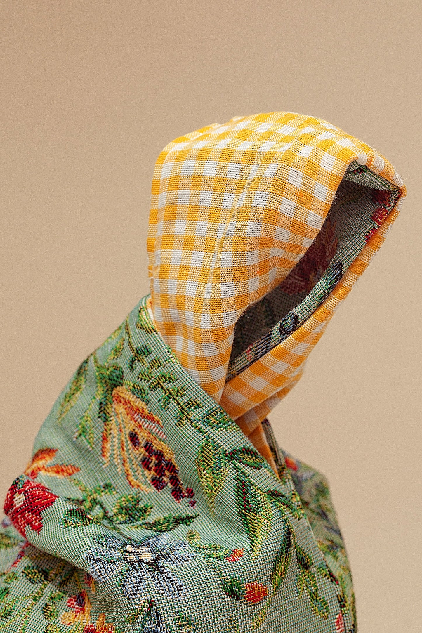 Chaqueta verde con bordados de flores y capucha a cuadros amarillos, estilo casual y material liviano.