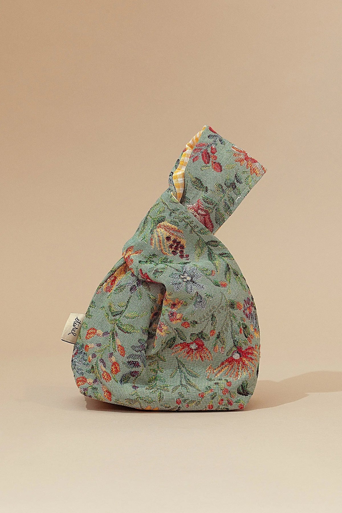 Bolso reversible de tela verde con flores en tonos rojo y amarillo, estilo bohemio. Ideal para el uso diario.