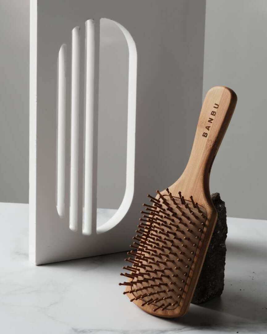 Cepillo de madera Banbu con cerdas largas sobre fondo minimalista blanco y gris. Diseño natural y sostenible.