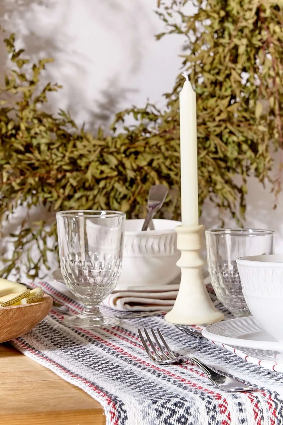 Camino de mesa artesanal granate, gris y blanco con tejido texturizado sobre una mesa decorada con vajilla elegante.