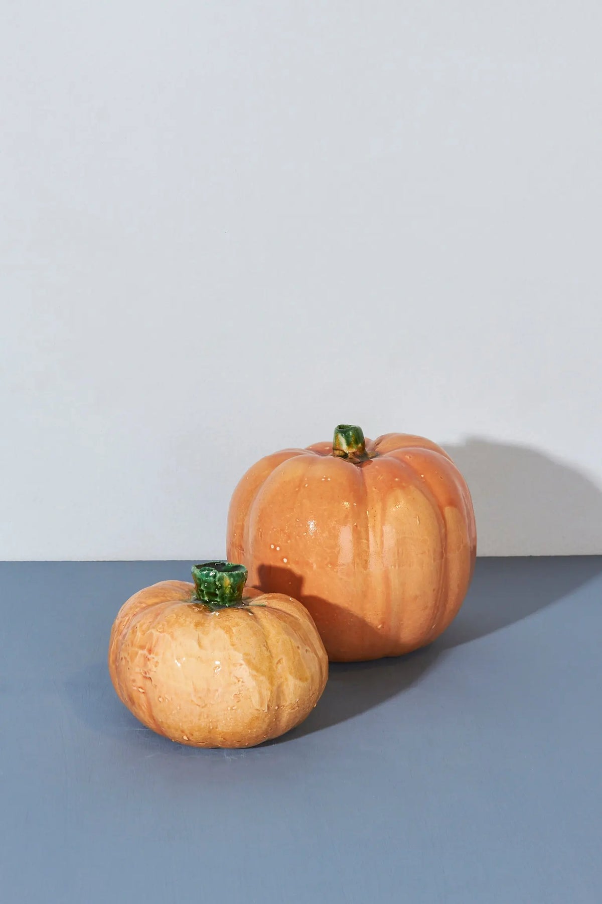 Calabazas decorativas de cerámica en tonos naranjas y verdes, ideales para adornos de otoño.