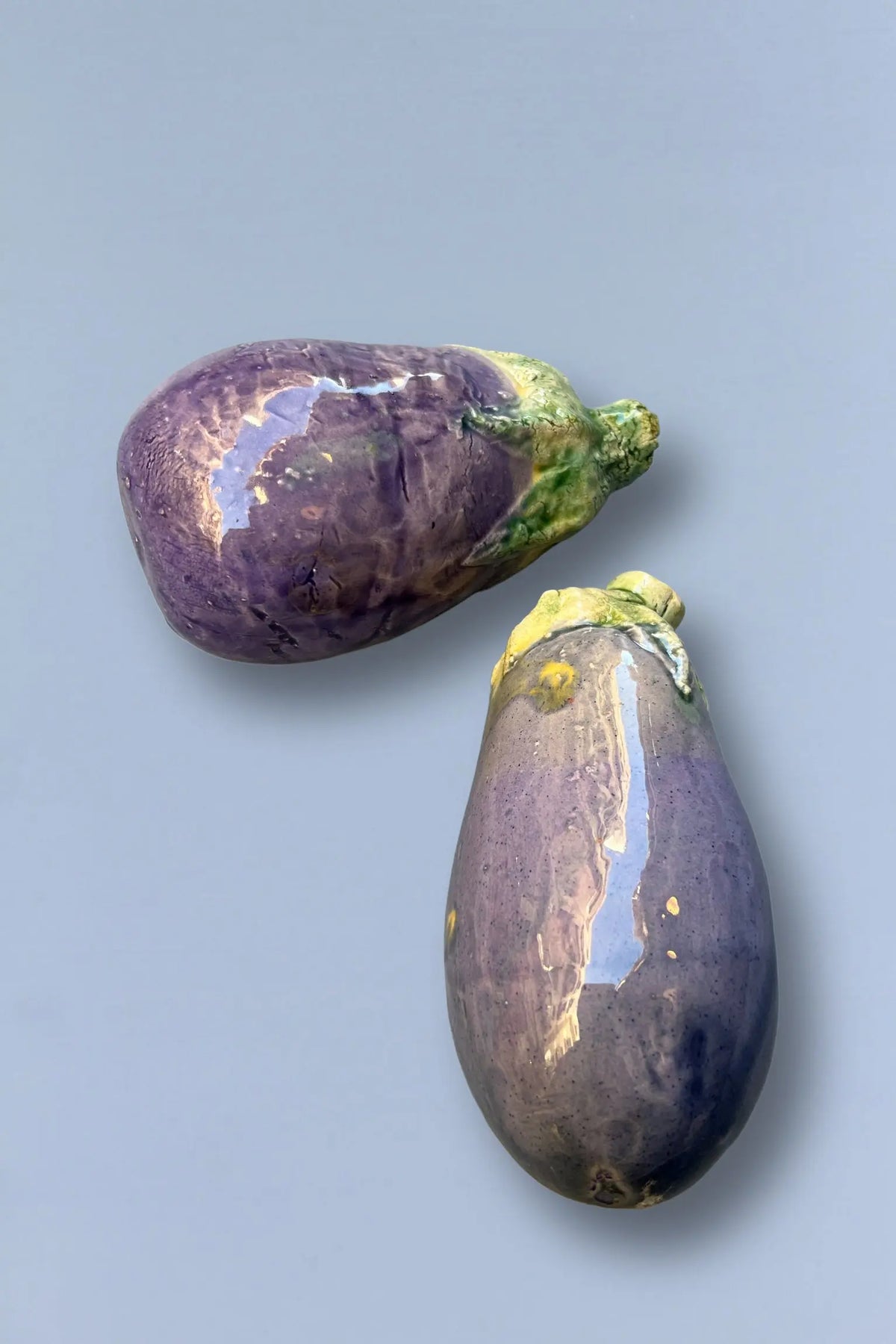 Berenjenas moradas brillantes, frescas y carnosas, ideales para cocinar o ensaladas, sobre fondo gris claro.