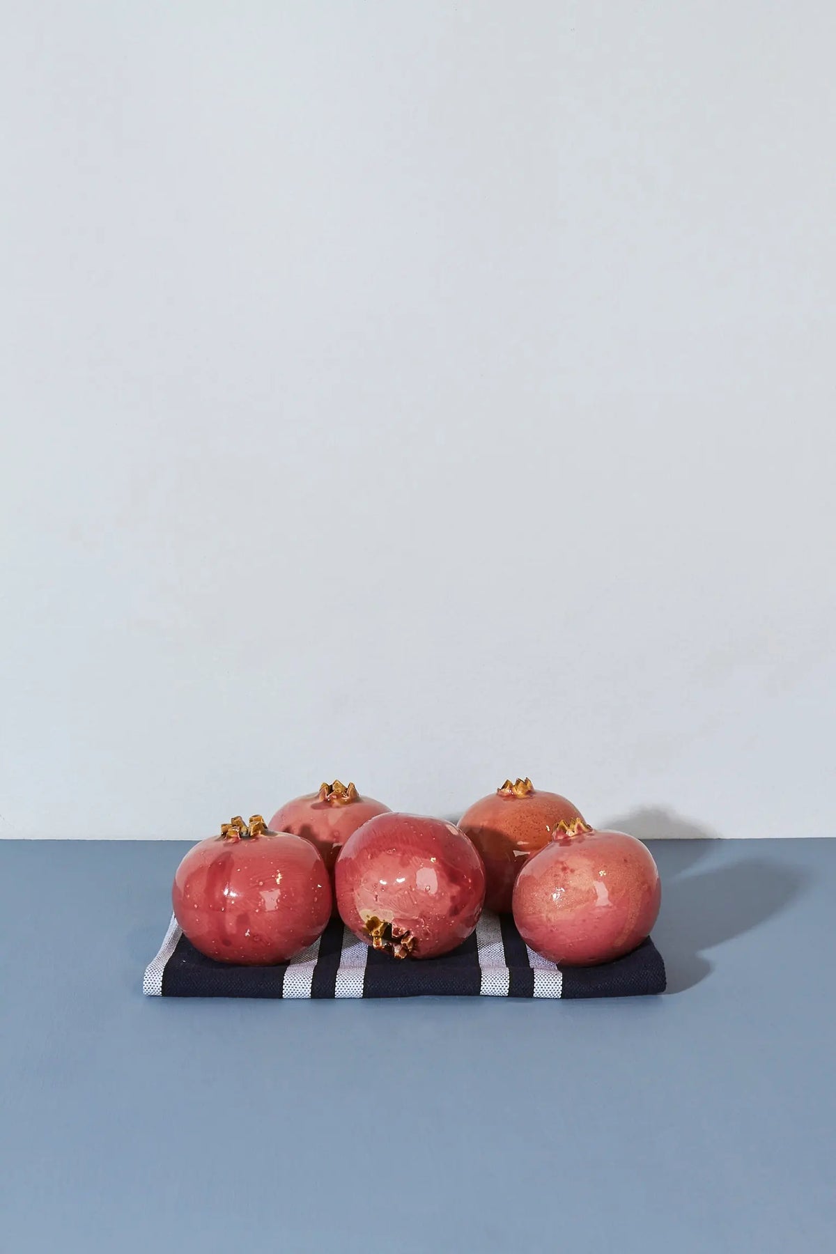 Granadas rosadas sobre una servilleta de rayas azules y blancas, con un fondo minimalista.