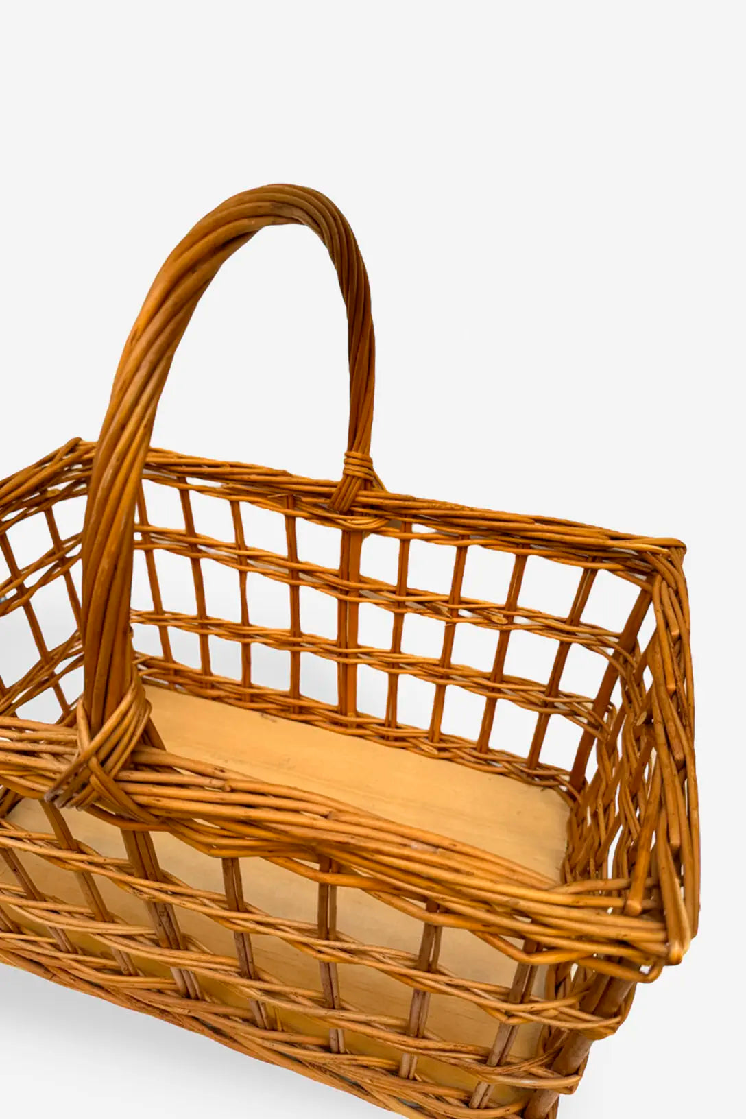 Cesta de picnic rectangular de mimbre natural con diseño calado de cuadrícula y asa central, sobre base de madera clara.