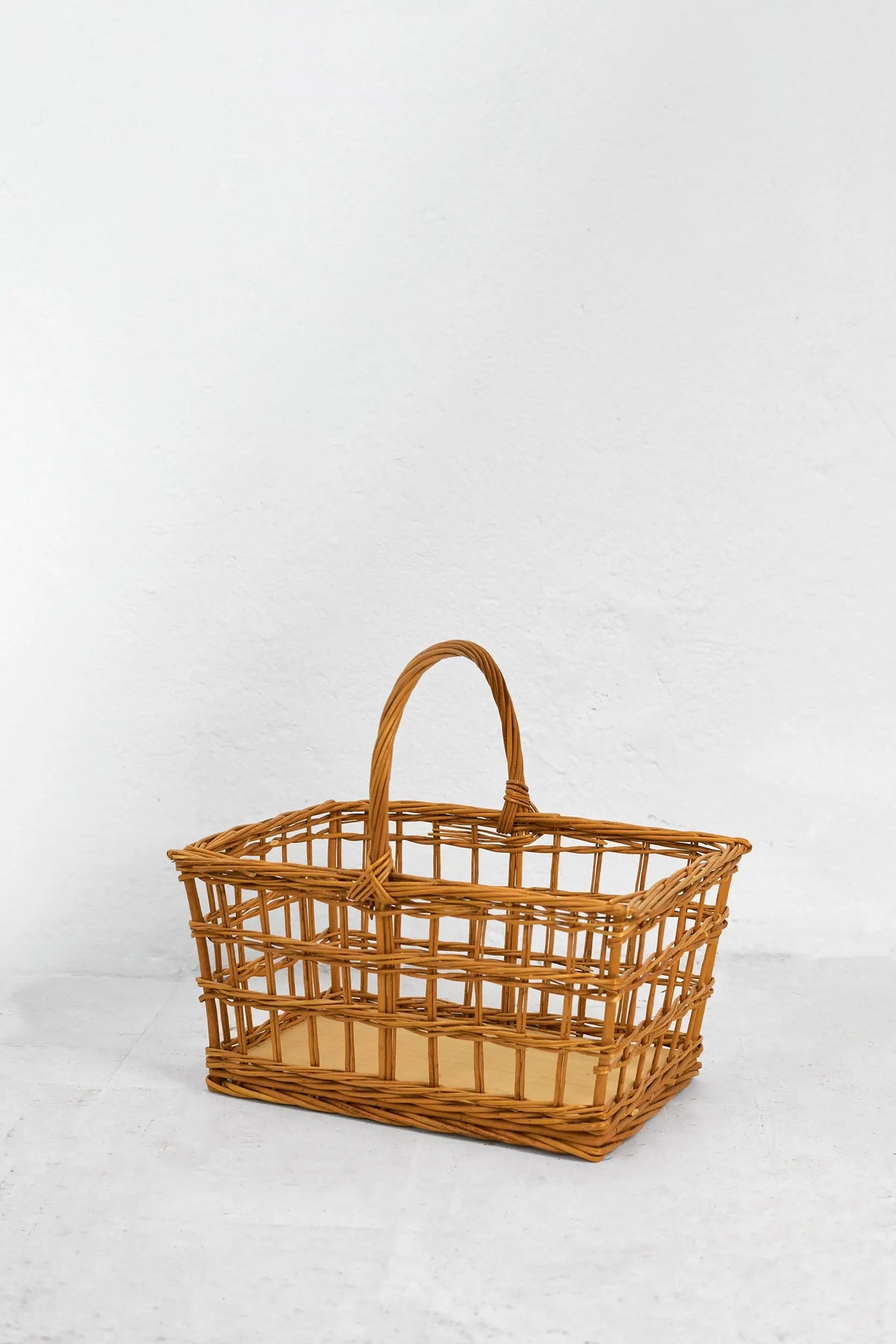 Cesta de picnic rectangular de mimbre natural con diseño calado, estructura abierta y asa central, sobre fondo blanco.