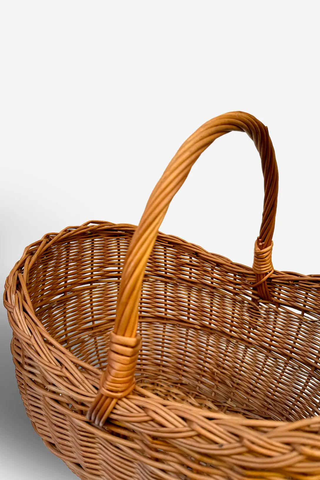 Cesta capazo de mimbre natural con trenzado artesanal y asa curva resistente, estilo rústico en color madera cálido.