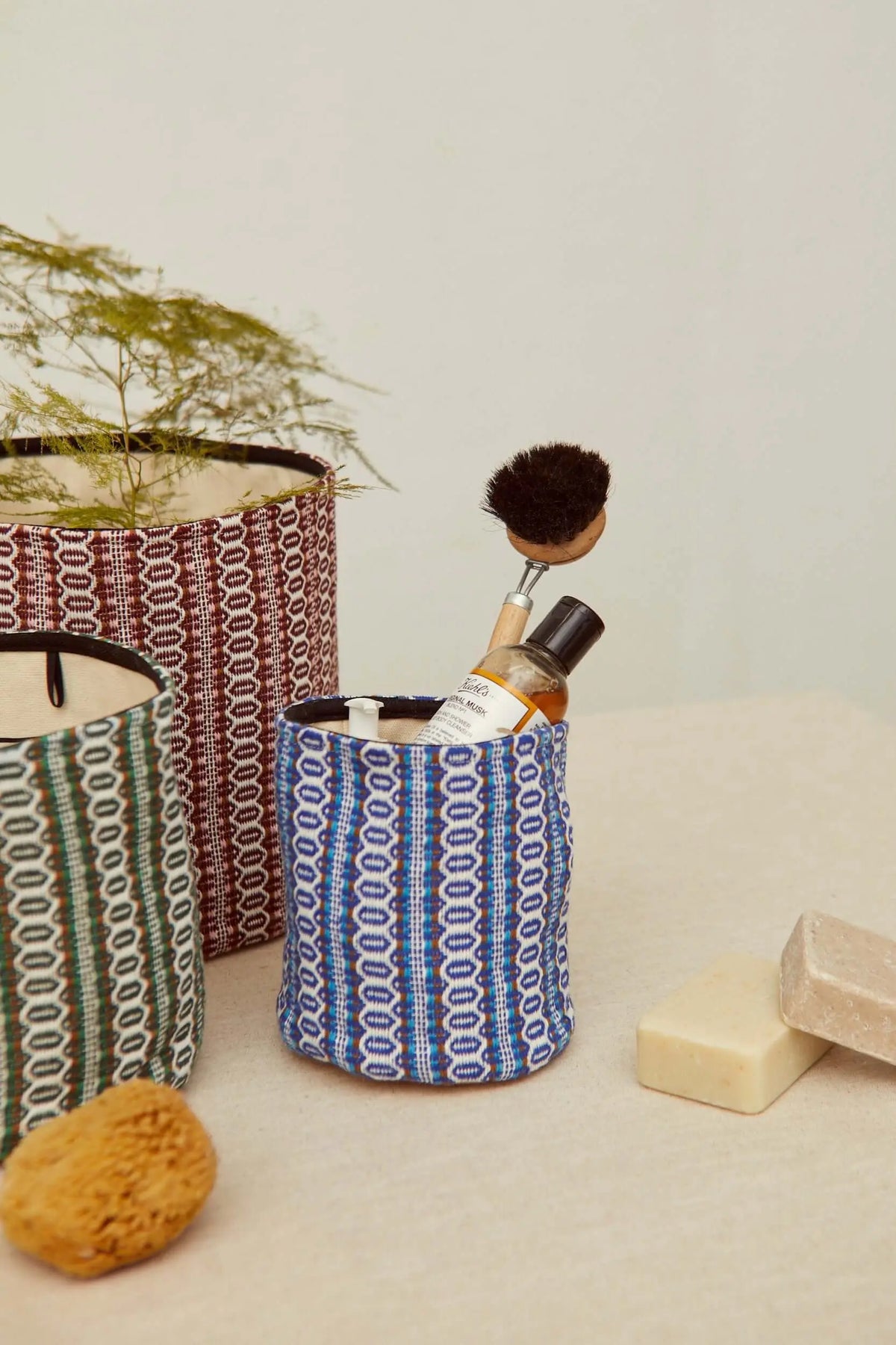 Cestos de tela retro con patrón ojo de perdiz en azul, granate y verde, ideales para organizar artículos de baño.