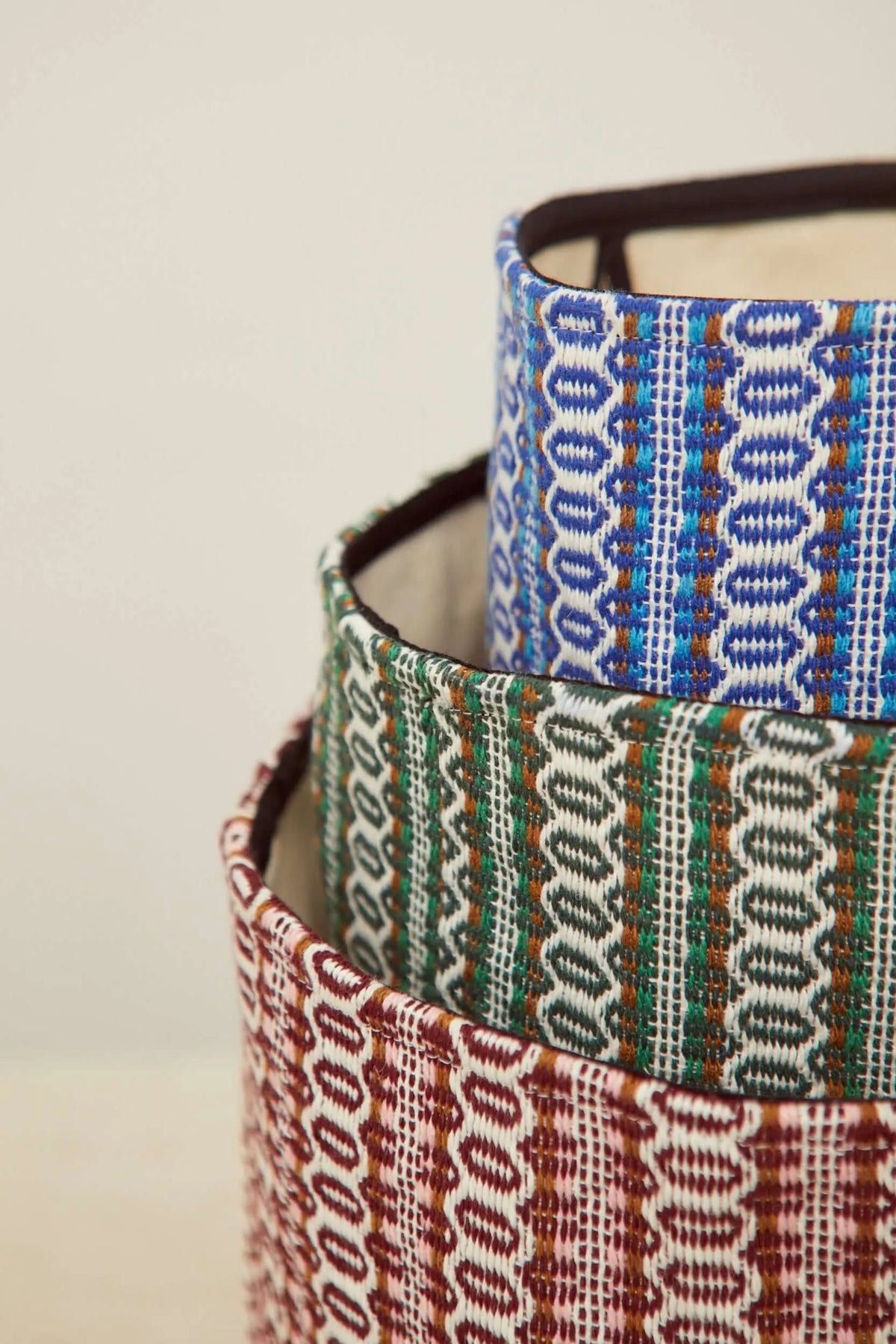 Cestos apilables con estampado ojo de perdiz en tonos azul, verde y granate, estilo retro con textura tejida.
