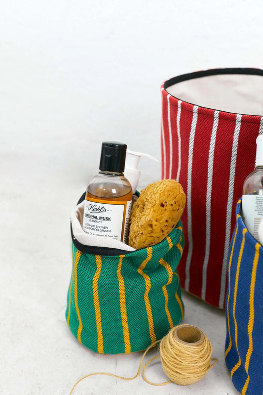 Cestos decorativos de algodón a rayas en colores granate, verde y azul para organizar accesorios de baño y cuidado.