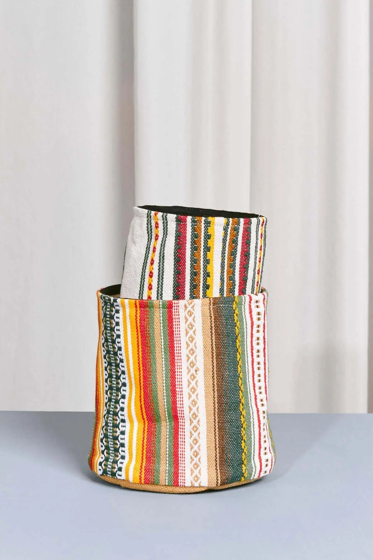 Cestos cilíndricos de tela con rayas verticales multicolores y patrones geométricos tradicionales.