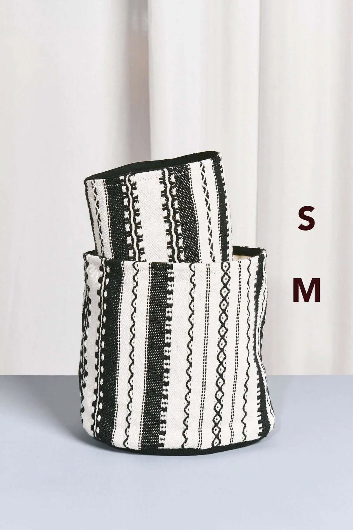 Cestos de tela estilo alpujarra con estampado de rayas y grecas geométricas en blanco y negro, diseño cilíndrico.