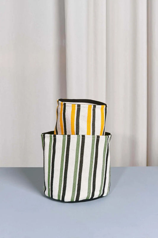 Dos cestos cilíndricos de loneta con rayas verticales: uno en blanco, negro y verde, y otro en blanco, negro y amarillo.