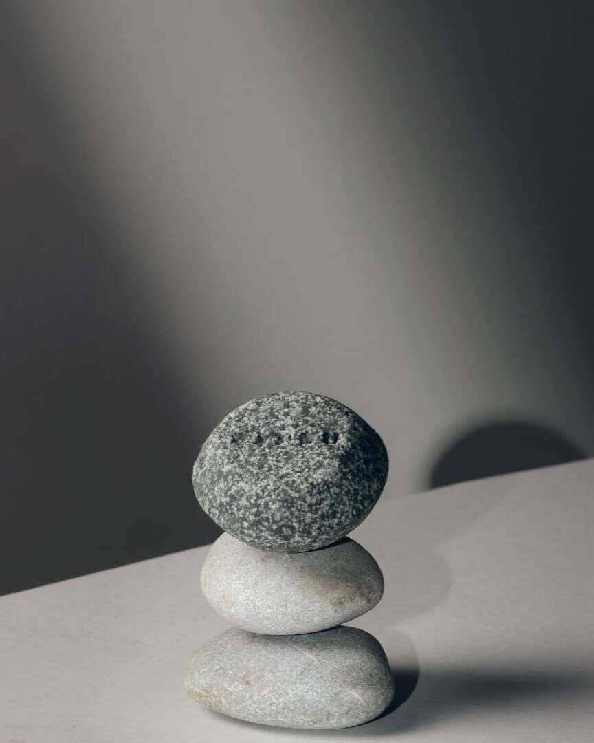 Champú sólido Mare de Banbu, gris jaspeado y textura rugosa, sobre una torre de piedras lisas en fondo gris minimalista.