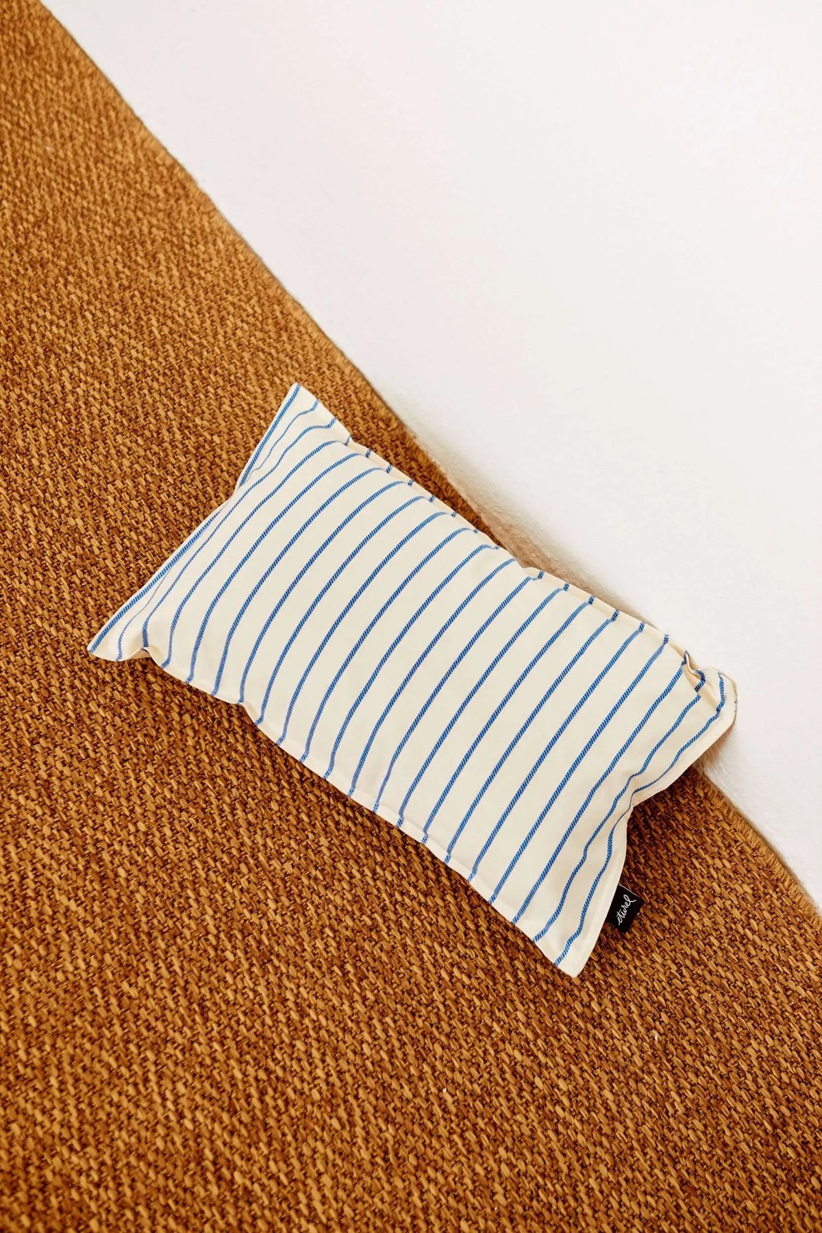 Rectangular 30x50cm cushion cover with vertical blue stripes on an off-white cotton fabric, placed on a brown surface.
