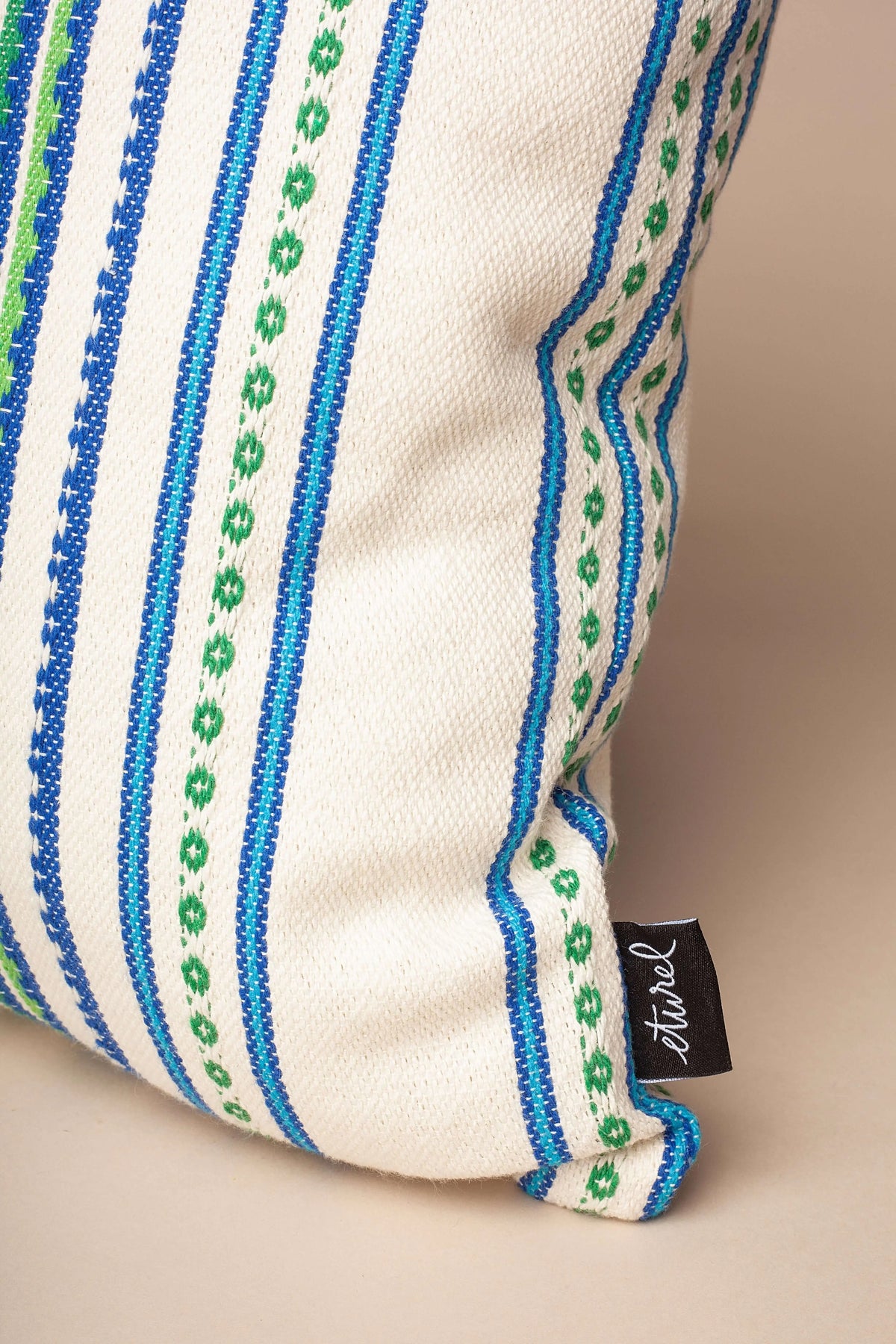 Funda de cojín de tela natural con estampado de rayas verticales en tonos azul y verde, estilo artesanal y texturizado.