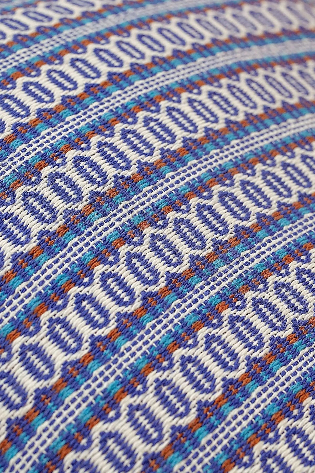 Funda de cojín con patrón geométrico retro estilo ojo de perdiz en tonos azul, blanco y detalles en terracota.
