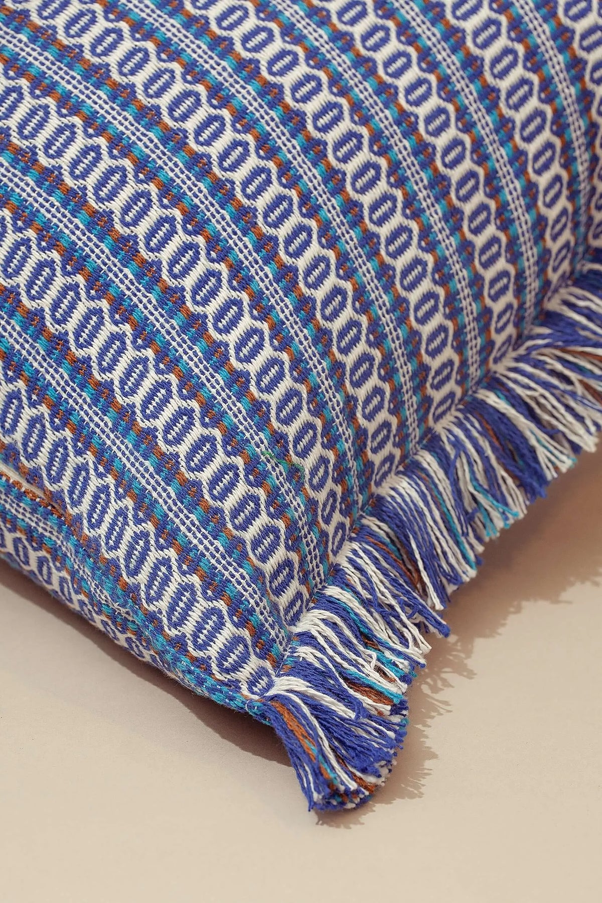 Funda de cojín 45x45cm con tejido ojo de perdiz azul, estilo retro, diseño de franjas y flecos decorativos en bordes.
