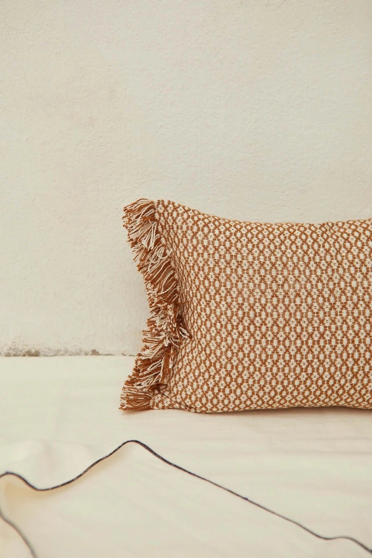 Funda de cojín rectangular 30x45cm en color caramelo, tejido tipo ojo de perdiz con flecos laterales y estilo artesanal.