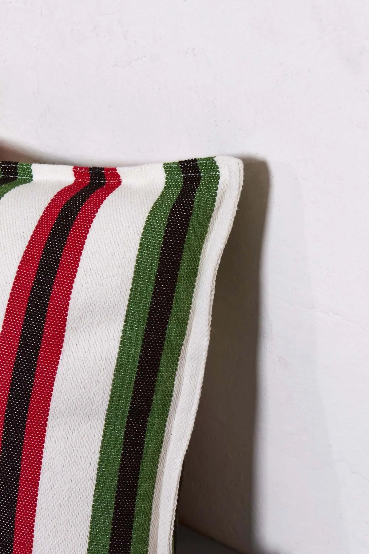 Rectangular cushion cover in cream fabric with vertical stripes in vibrant red, green, and black, textured weave.