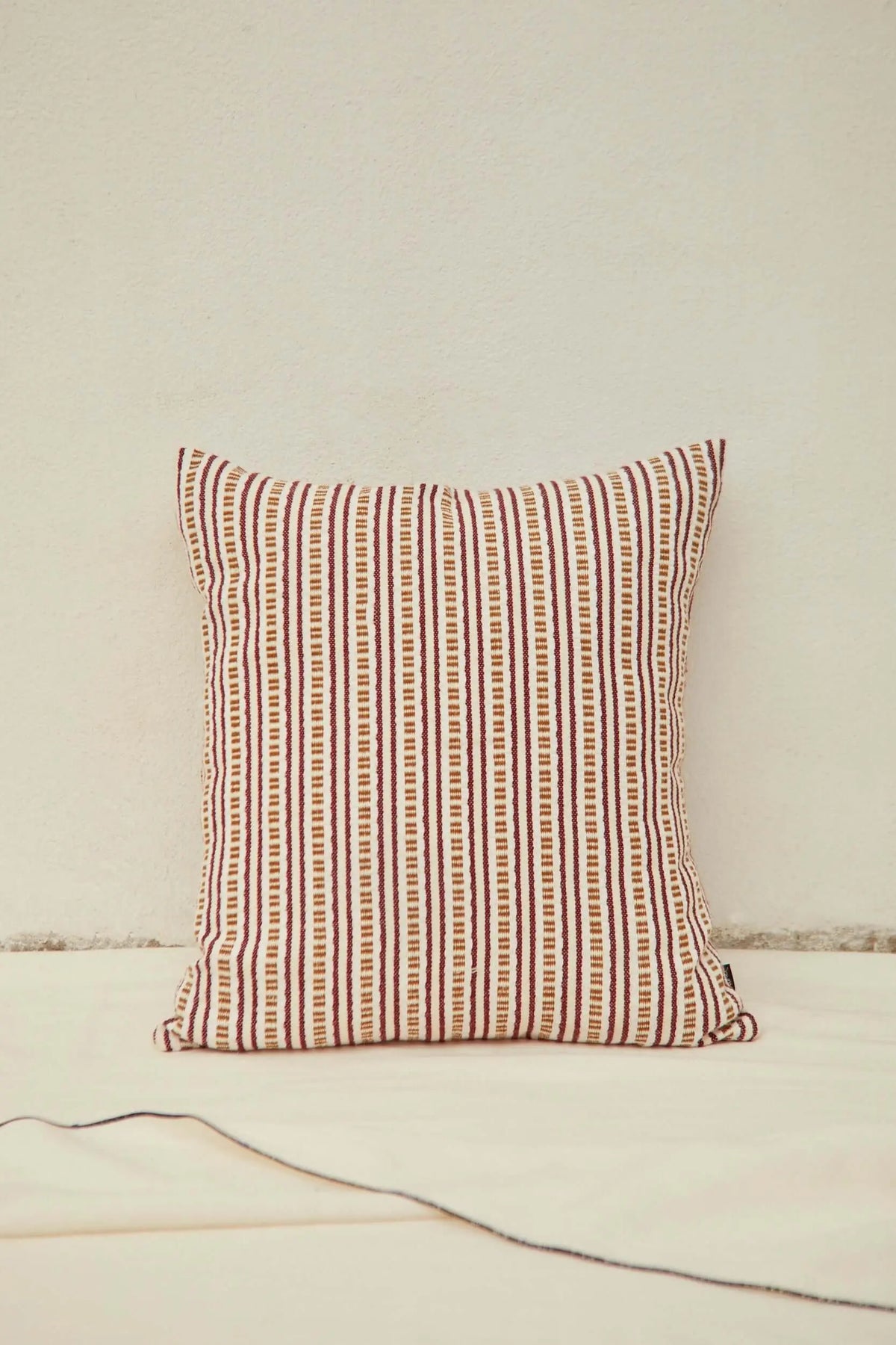 Square cushion cover with vertical dark red and beige striped pattern on a textured, woven fabric.