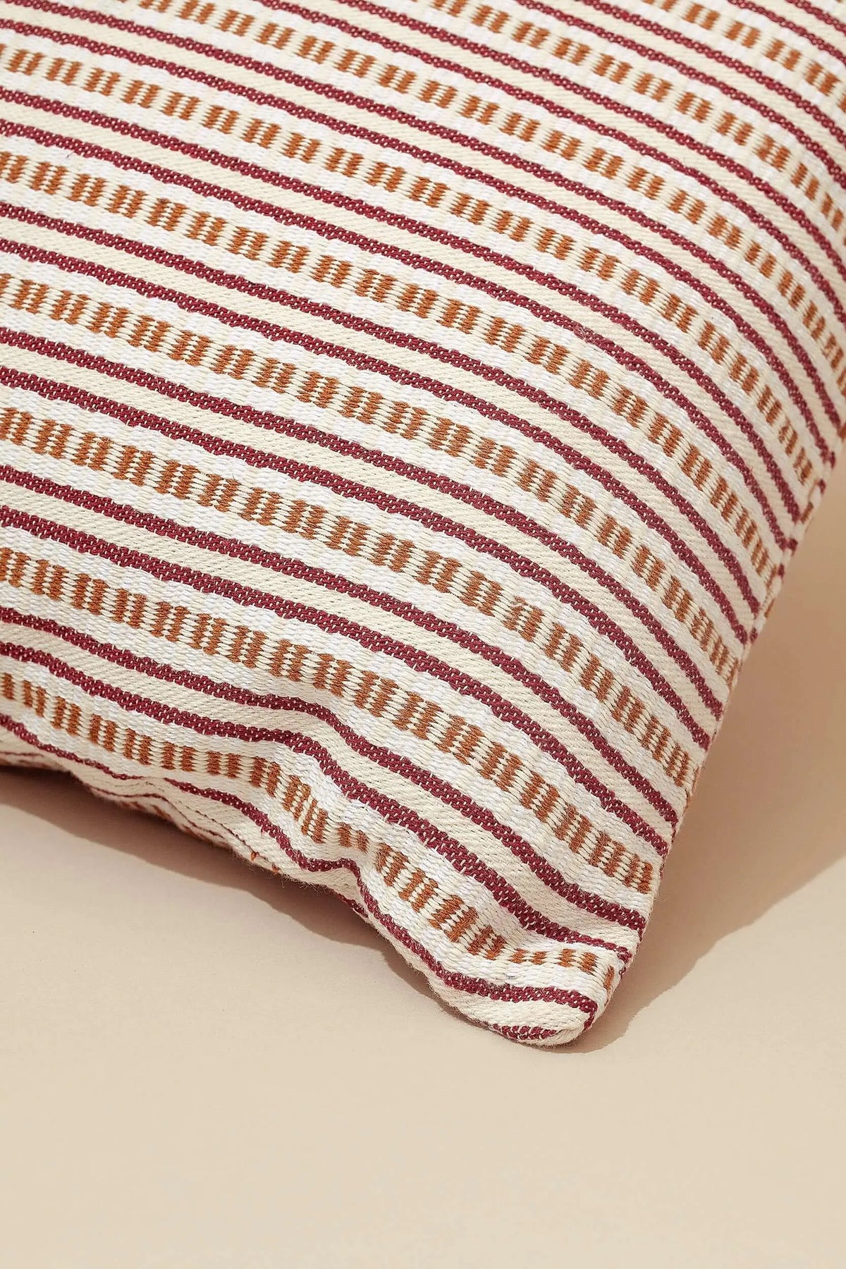Funda de cojín 50x50 cm de tejido texturizado con rayas horizontales en tonos granate y beige, estilo rústico decorativo.