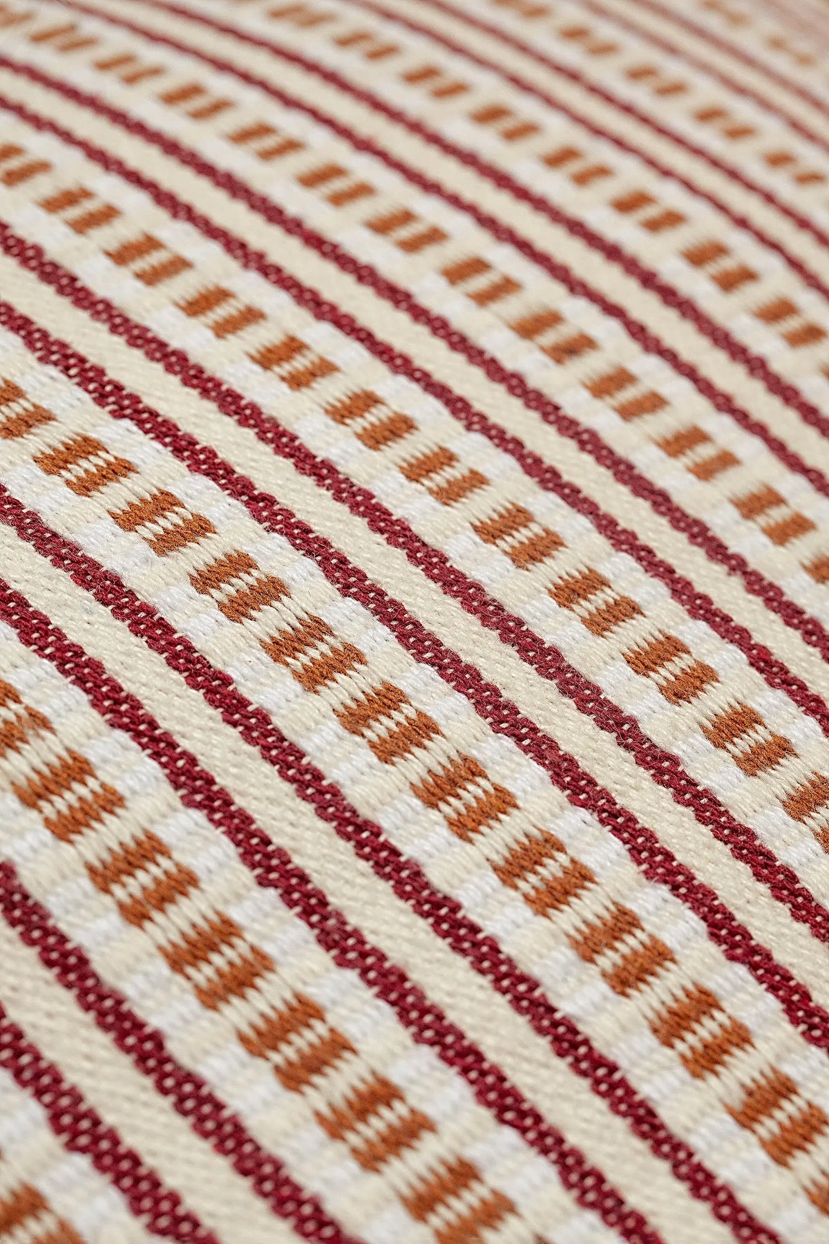 Panera de tela con patrón de rayas verticales en tonos crudo, granate y ocre, con textura rústica y estilo artesanal.
