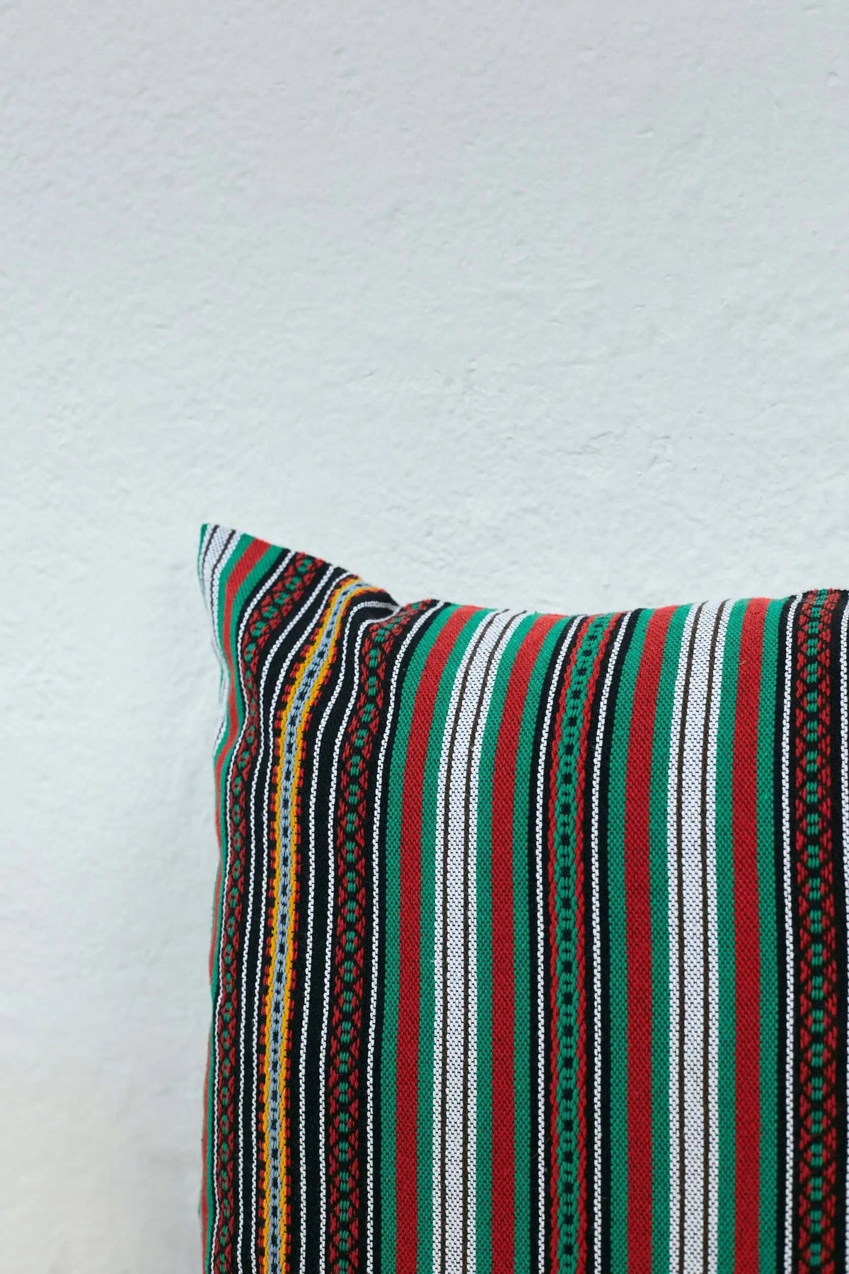 Rectangular pillow cover with a vibrant striped pattern in green, red, black, and white traditional textile weave.