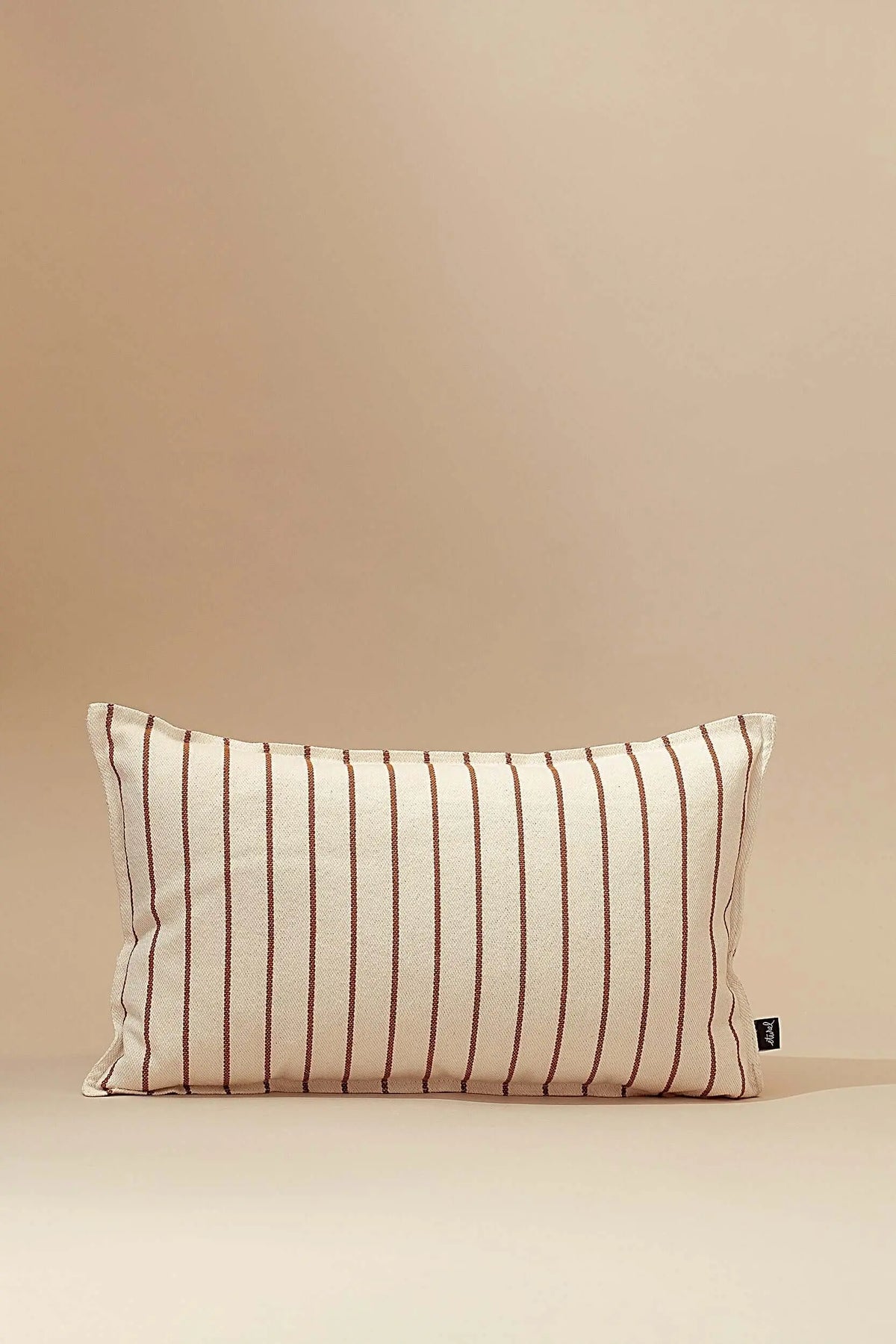 Funda de cojín rectangular de loneta en color crema con rayas verticales finas en tono caramelo, estilo rústico.