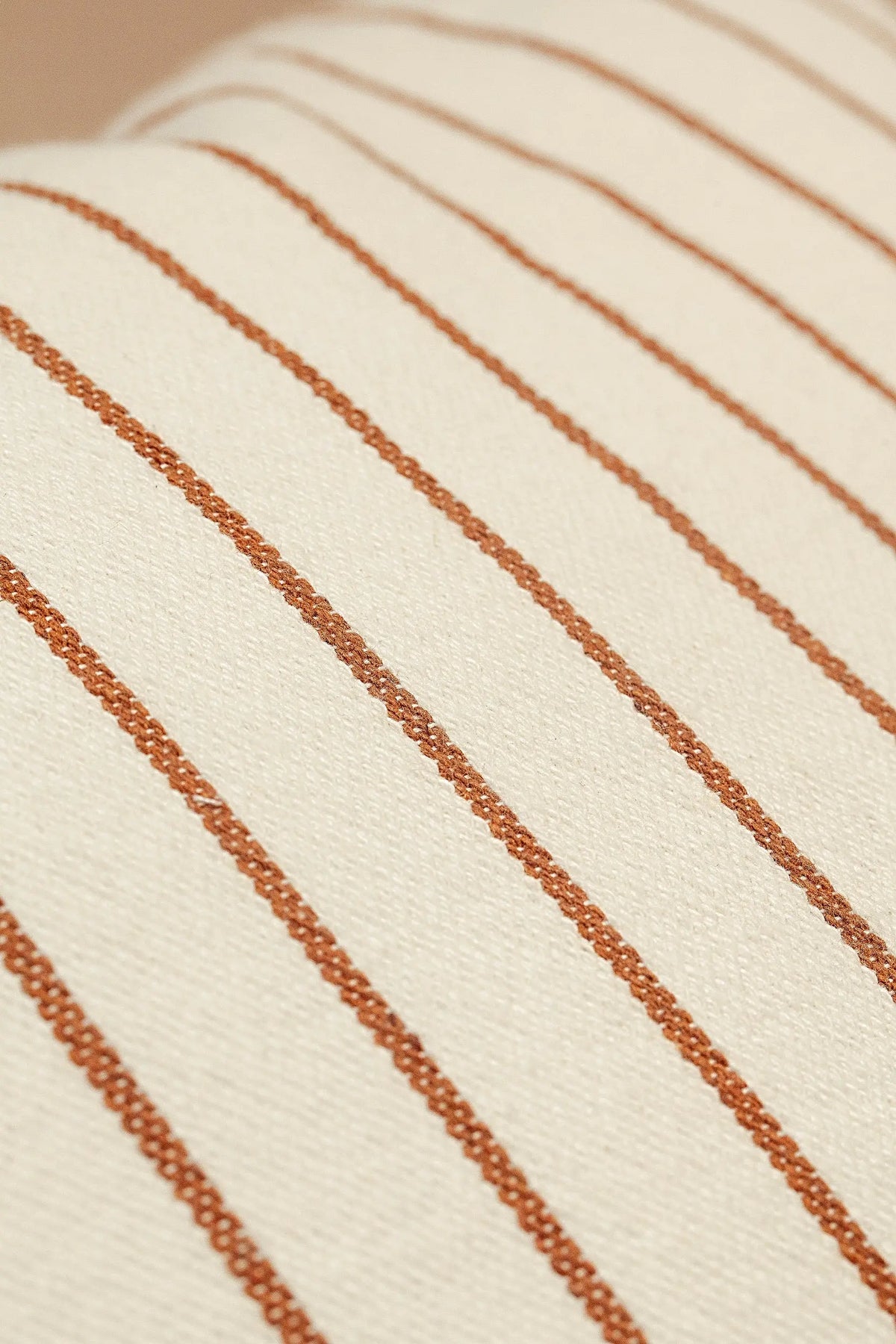 Funda de cojín de loneta color crema con rayas verticales finas en tono caramelo, estilo rústico y elegante.
