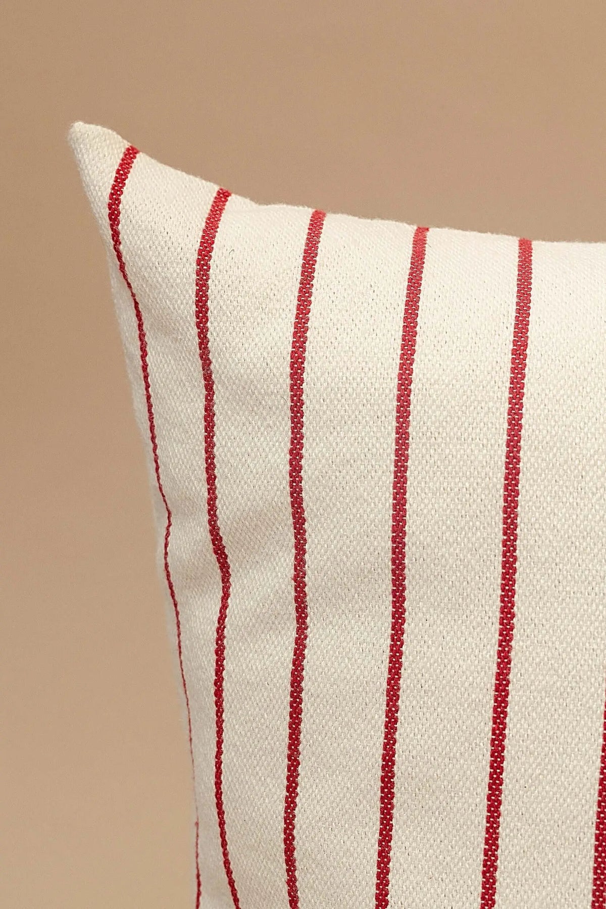 Funda de cojín de loneta color crudo con rayas verticales granates, de textura resistente y diseño sencillo.