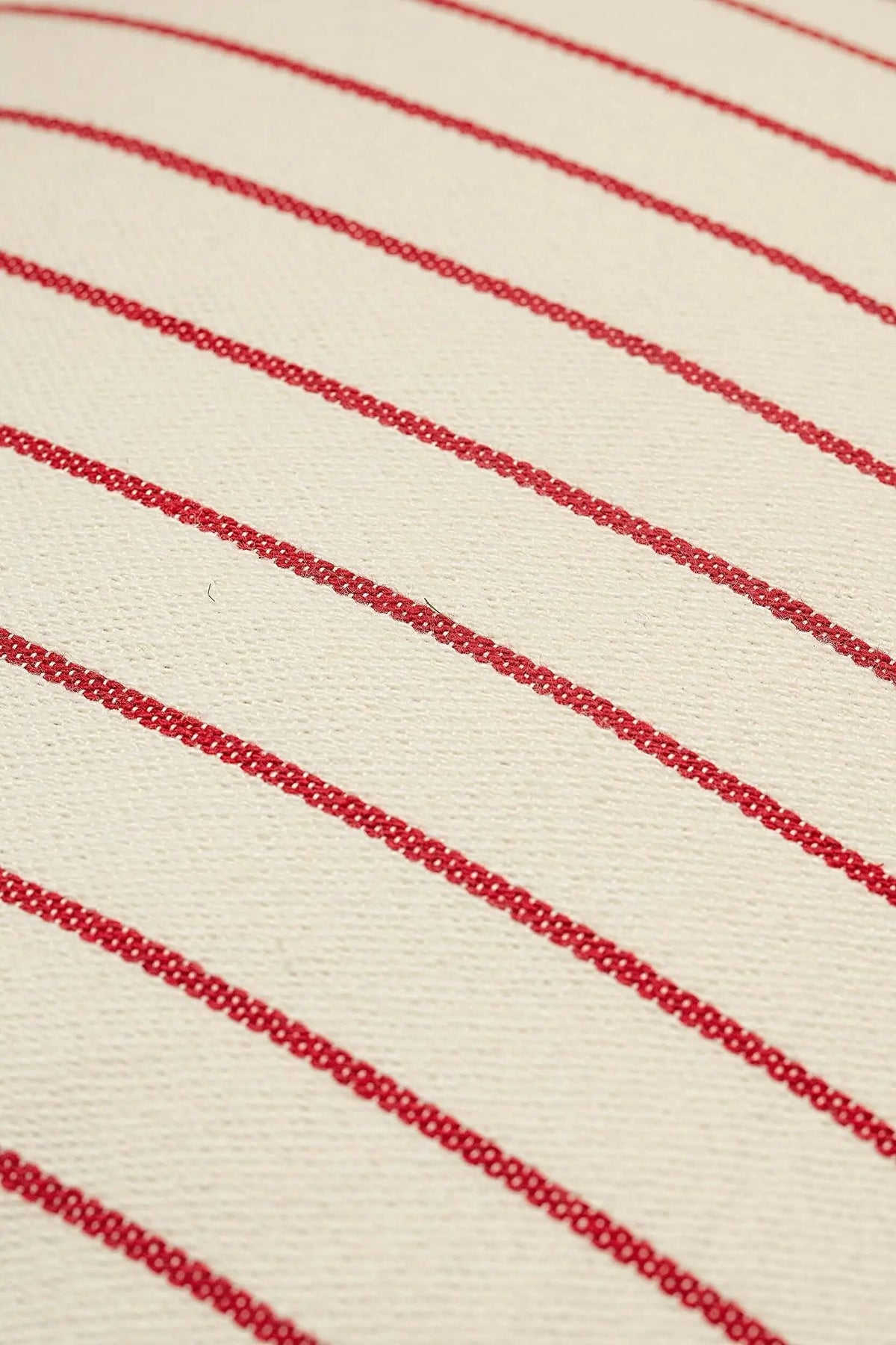 Funda de cojín de loneta beige con finas rayas diagonales en color granate y textura de tejido natural.