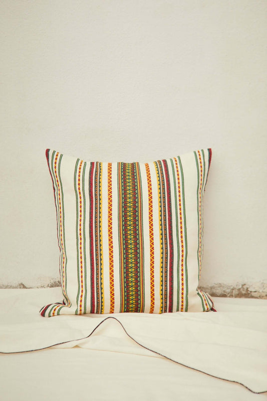 Square cushion in cream fabric with a colorful, traditional Manchego-style vertical striped pattern.