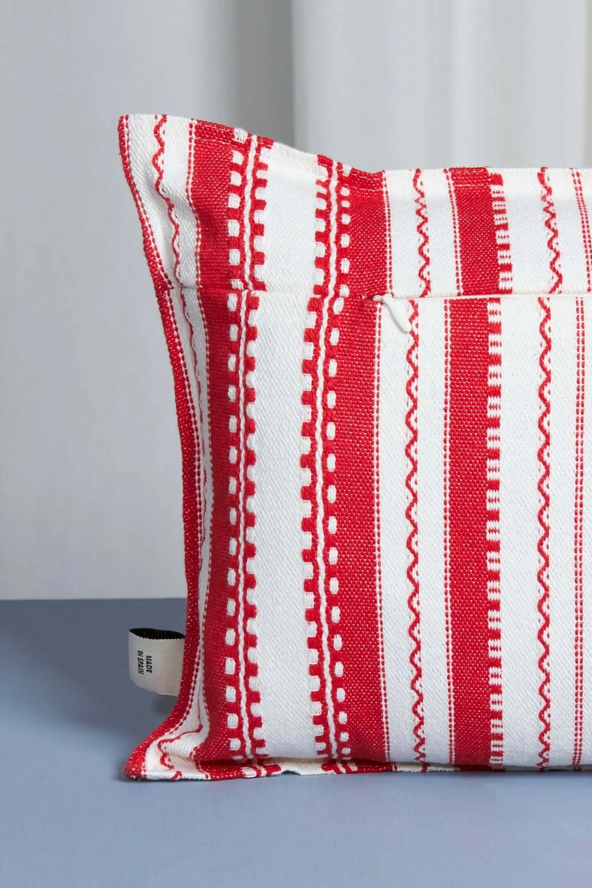 Funda de cojín rectangular con rayas verticales rojas y blancas, tejido estilo alpujarra con cierre de cremallera.