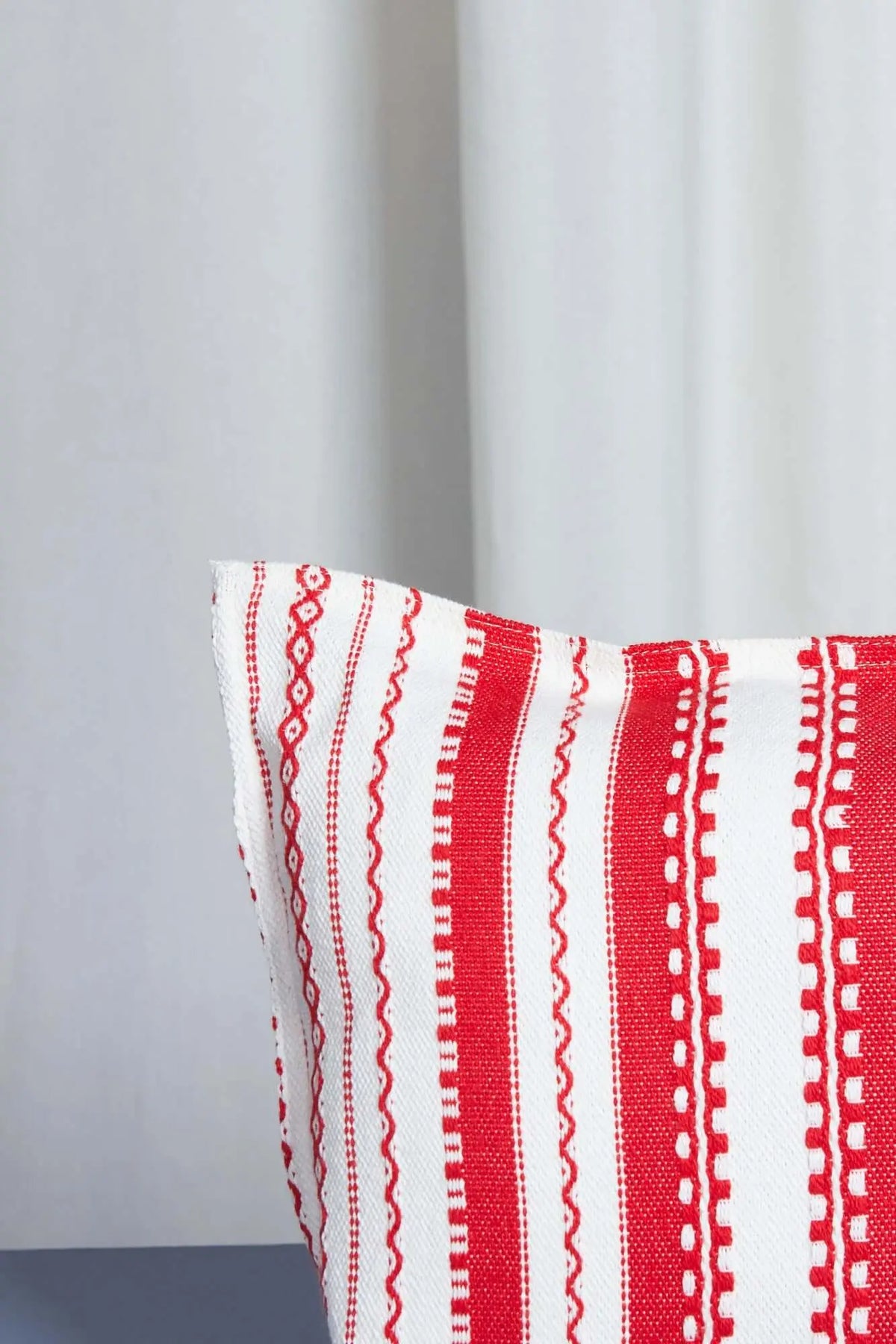 Funda de cojín rectangular con tejido de rayas verticales rojas y blancas, estilo tradicional artesanal.