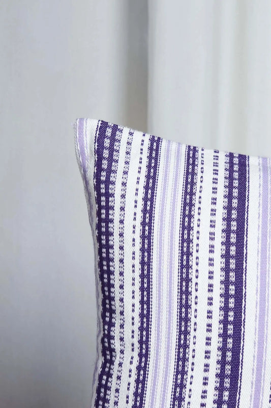Funda de cojín 50x50 cm estilo alpujarreño, tejido de rayas verticales en tonos morado y malva sobre fondo blanco.