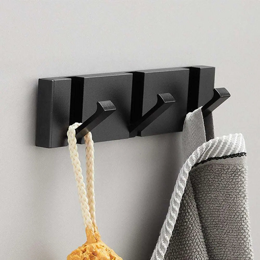Perchero de pared moderno de metal negro con tres ganchos abatibles, ideal para colgar toallas y accesorios.