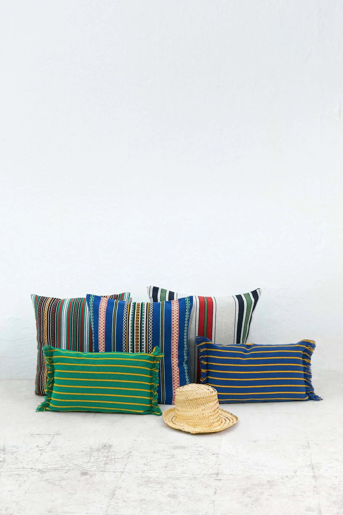 Funda de cojín verde de 50x45cm con rayas horizontales amarillas y flecos laterales, estilo artesanal y decorativo.