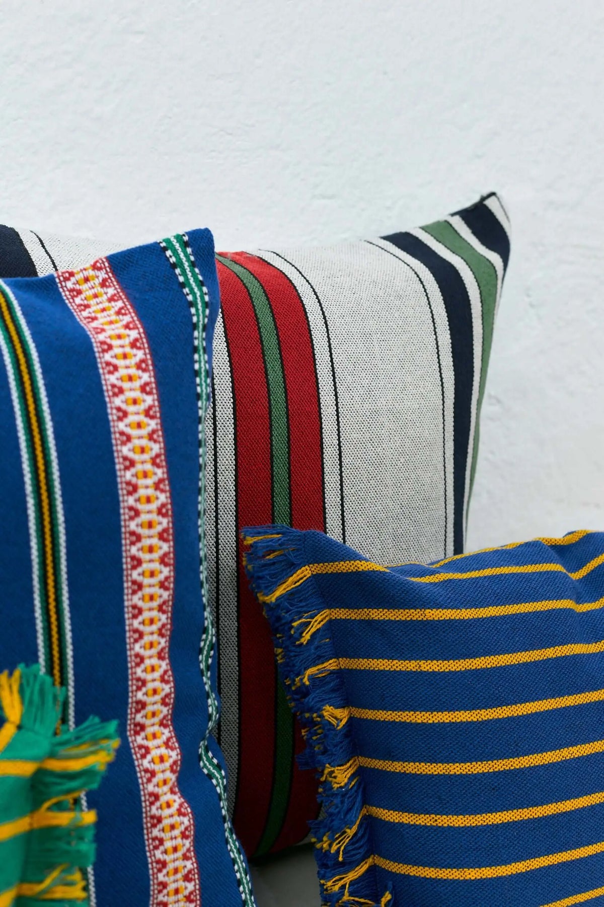Funda de cojín de 30x45cm con rayas multicolores en tonos azul, granate, verde y amarillo, tejido de estilo artesanal.