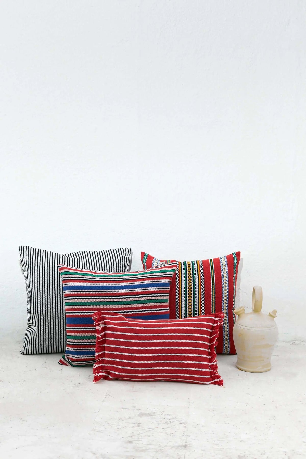 Funda de cojín rectangular de 30x45cm con rayas rojas y blancas, estilo rústico con flecos laterales.