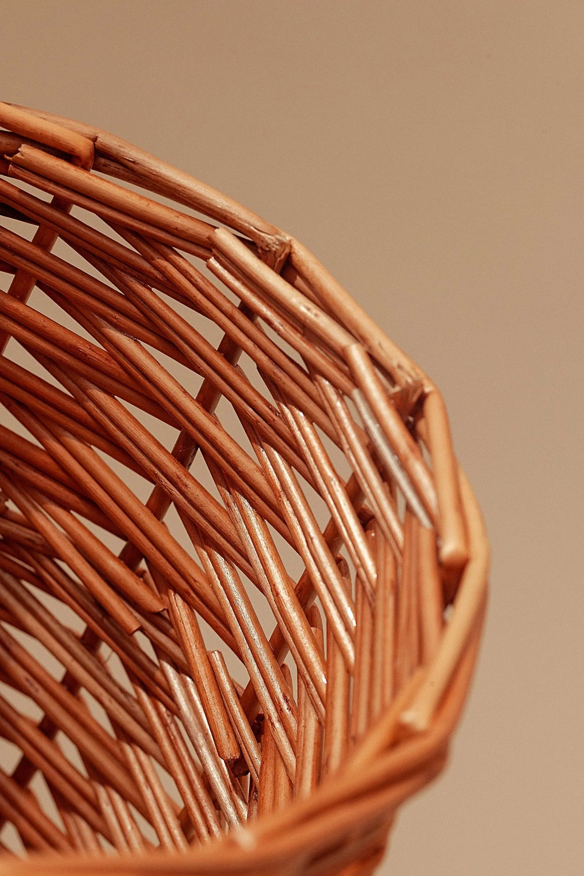 Primer plano de un jarrón pequeño de mimbre natural con textura artesanal en tonos marrones sobre fondo neutro.