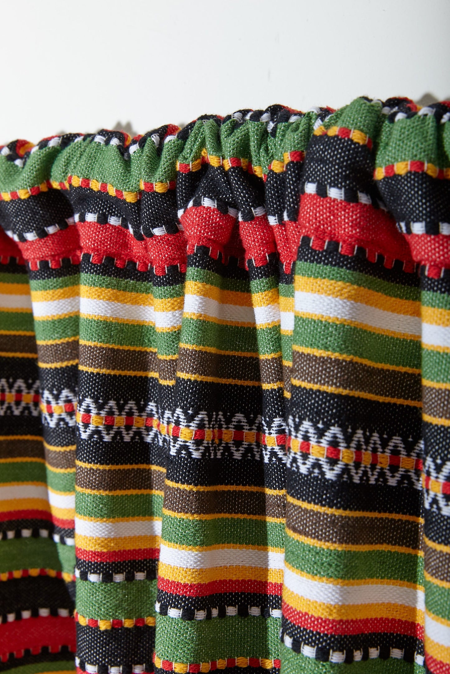 Cortina de algodón multicolor con estampado rayado en verde, rojo, amarillo y negro. Ideal para decoraciones vibrantes.