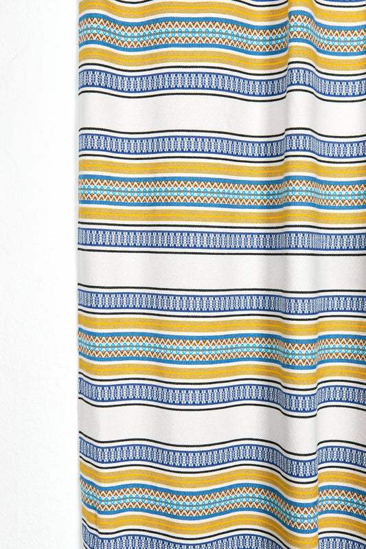 Cortina de tela blanca con rayas amarillas, azules y patrones geométricos, ideal para decorar cualquier habitación.