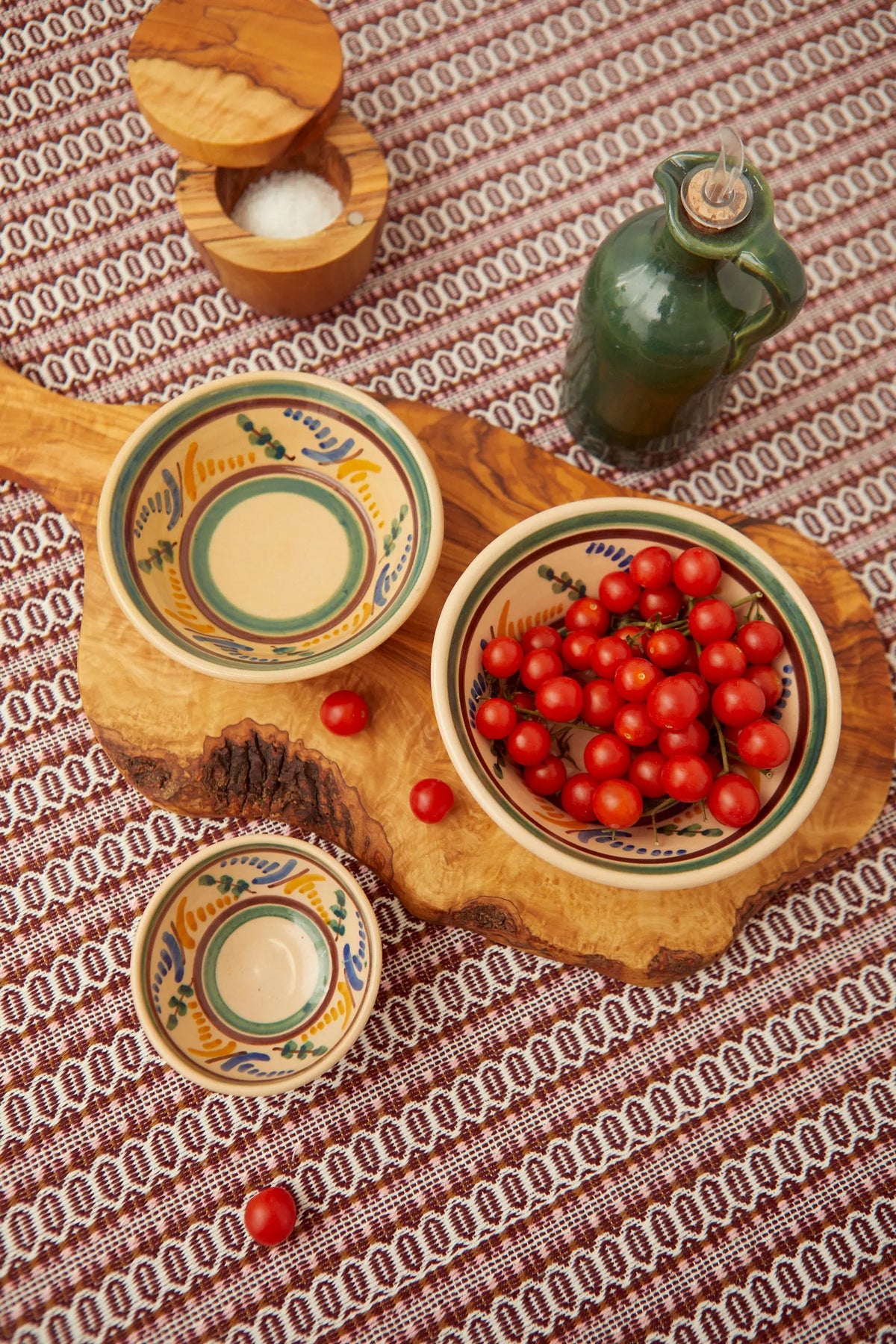 Set de cuencos de cerámica con estampado artesanal en tonos verdes y azules, sobre tabla de madera rústica.
