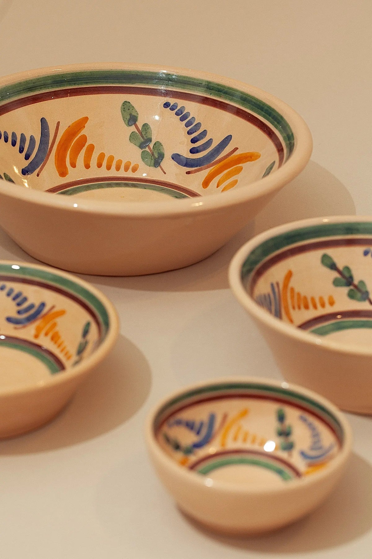 Set of three nested ceramic bowls with hand-painted blue, green, and orange folk-art floral patterns.