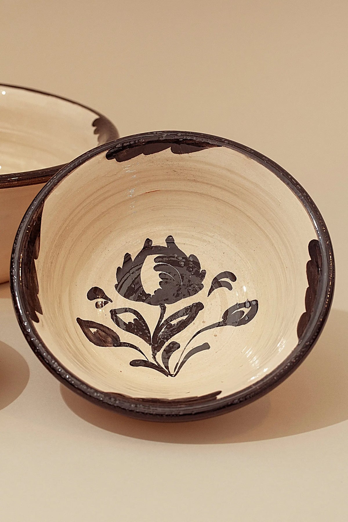 Cuencos de cerámica artesanal color crema con diseño floral pintado a mano en negro y bordes oscuros estilo tradicional.