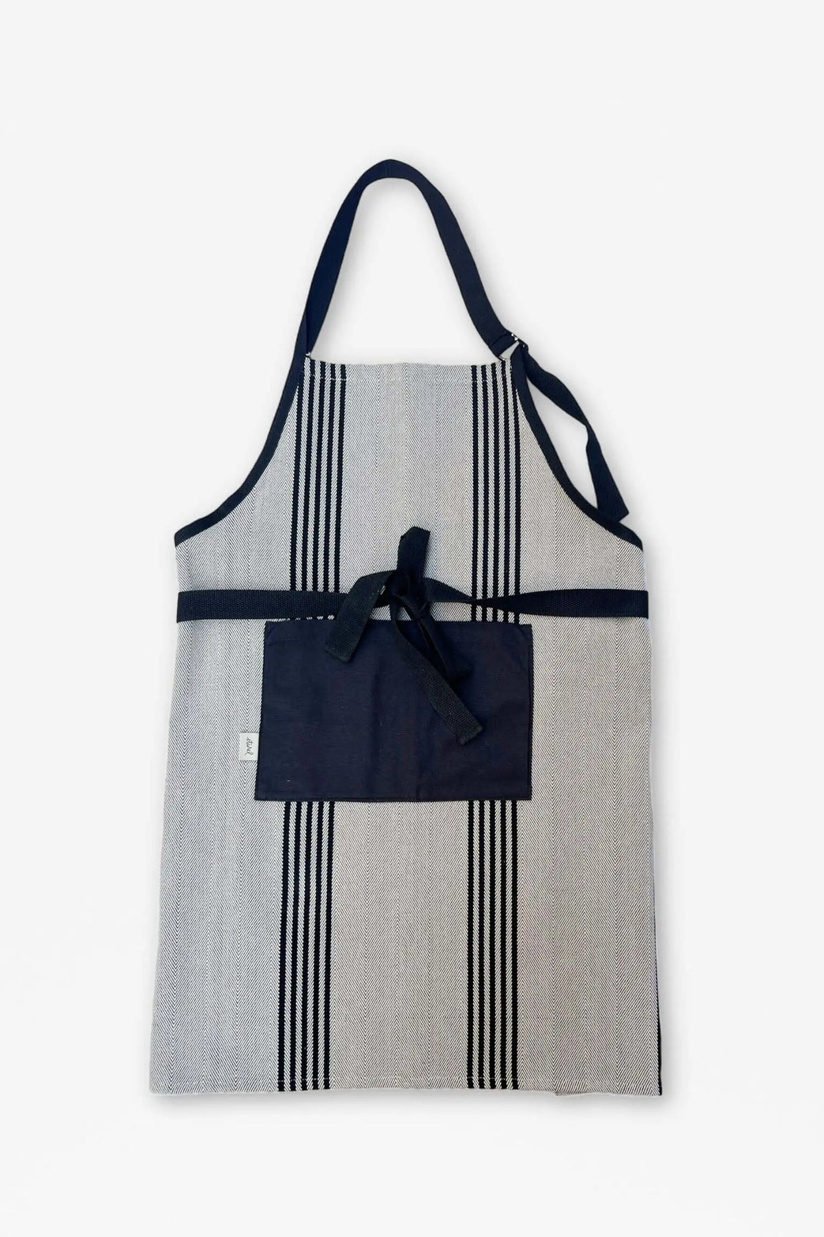 Delantal de sarga gris con rayas verticales negras, bolsillo central, tiras negras y acabado estilo rústico.