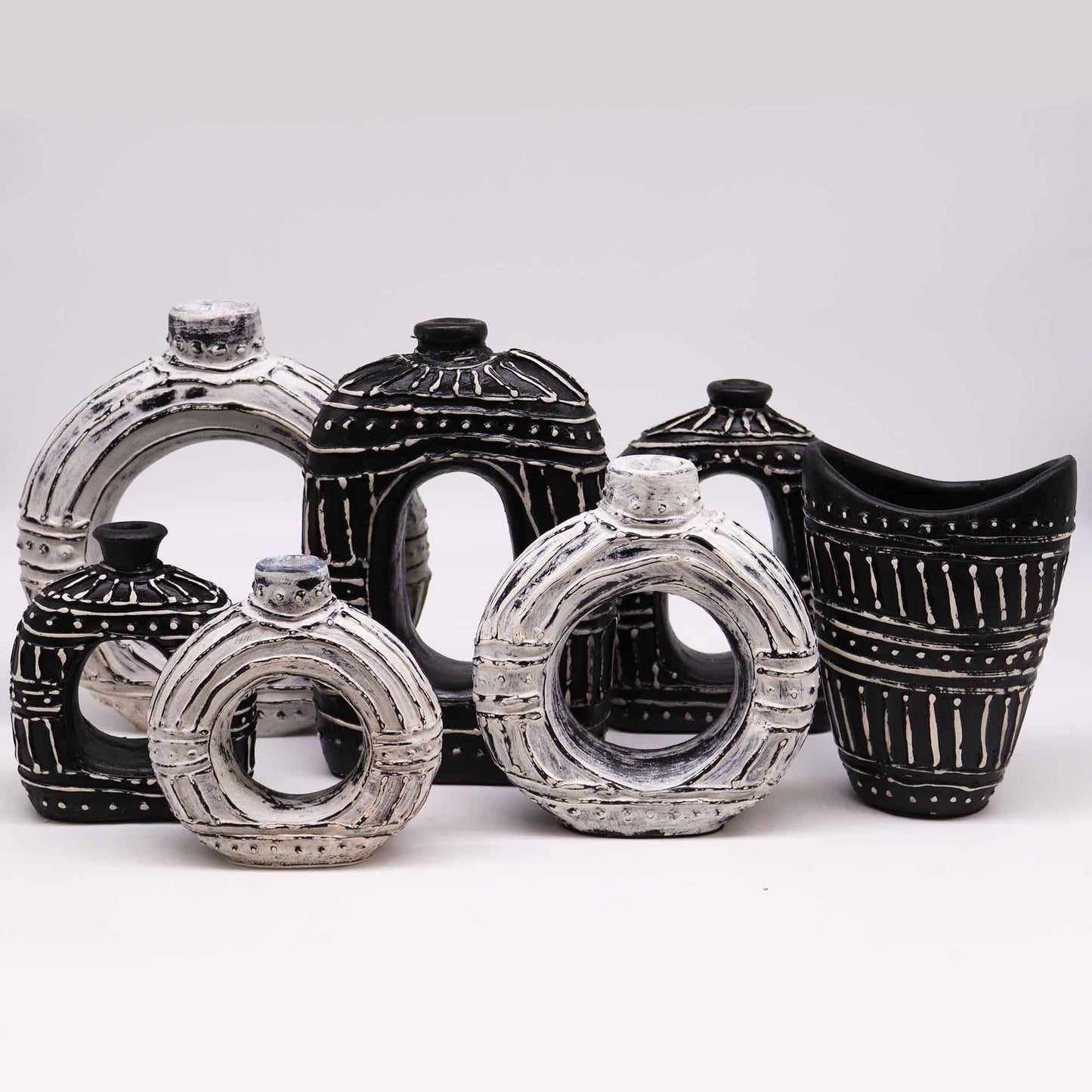 Grupo de jarrones de cerámica con formas circulares y ovaladas, estilo artesanal en tonos blanco y negro.