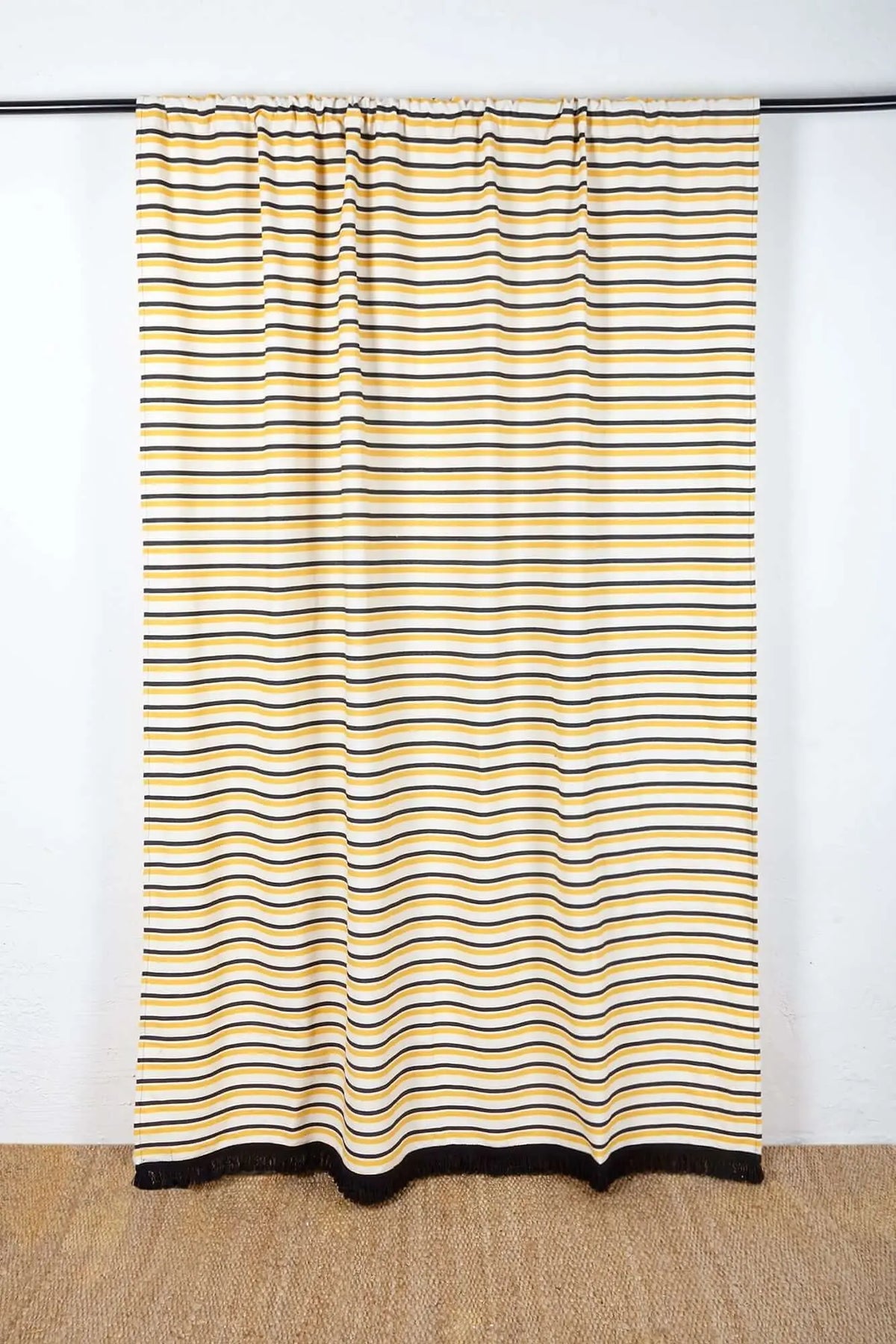 Cortina de loneta con rayas horizontales en amarillo, negro y blanco, estilo casual con flecos en el borde inferior.
